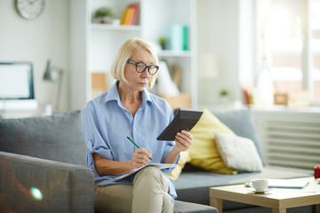 Portrait of contemporary mature woman calculating finances and budget at home, copy space