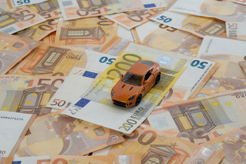 Ein Modellauto auf flächendeckend ausgelegten 50-Euro-Banknoten mit 200-Euro-Banknote zum Thema...