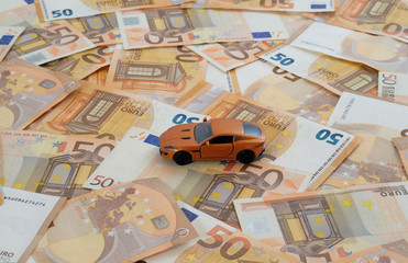 Ein Modellauto auf fl&auml;chendeckend ausgelegten 50-Euro-Banknoten zum Thema Konzept Autokosten