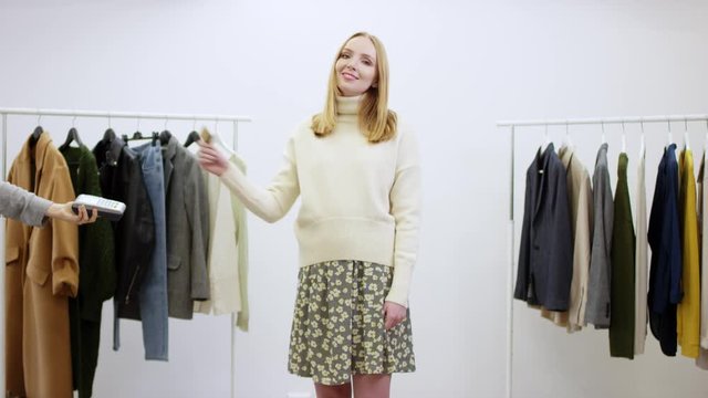 Aduit woman pays the bill by using pay wave technology on her credit card in a clothing shop