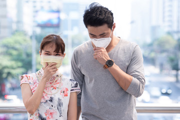 Asian man and woman wearing protective masks against air smog and tightening their mask, Asia traveler wear mask protection, air pollution in Bangkok city, Thailand,
