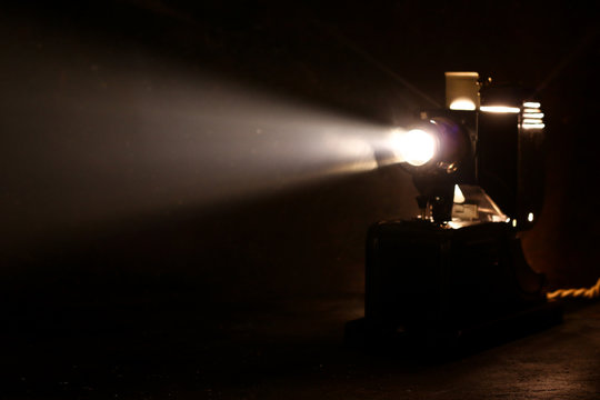 Old Film Projector, Running And Projecting With Visible Beam Of Light. Old Slide Projector On Dark Background. Vintage Projector Side View. Selective Focus.