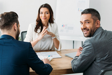 selective focus of investors in suits talking with attractive advisor at workspace