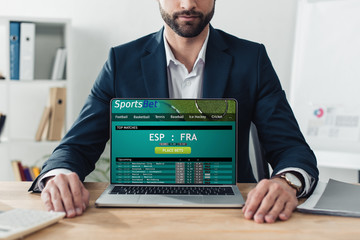 cropped view of advisor in suit showing laptop with sportsbet website on screen at office