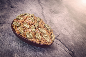 Chocolate egg with filling for Easter on wooden background.