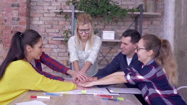successful team spirit, happy office workers men and women Hands stacked together moving up and down while Brainstorming on new business idea development project in modern office