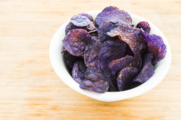 Heap of purple potato chips on wooden background