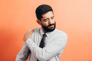 Portrait of young business man suffering from shoulder pain