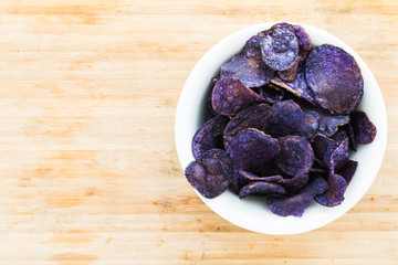 Heap of purple potato chips on wooden background