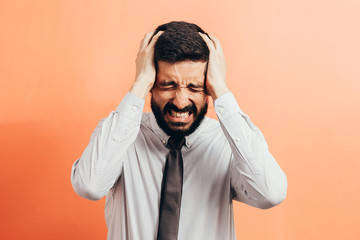 Portrait of an annoyed businessman suffering from a headache isolated on color background