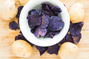 Heap of purple potato chips on wooden background