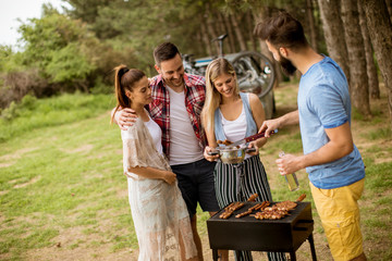 Group of young people enjoying barbecue party in the nature