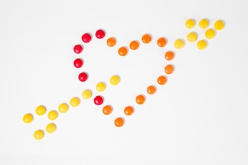 Shape of heart pierced with arrow - symbol of love - made from colorful sweet candies.