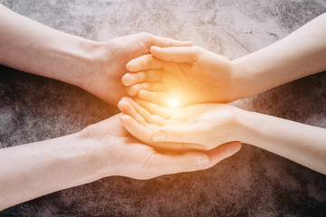 Light in young family hands offering help, protection and support symbol. Sharing hope concept