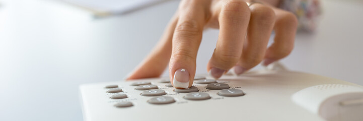 Woman with perfect french manicure dialing a telephone number