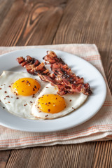 Fried eggs and bacon on the white plate