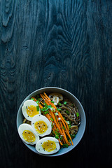 Buckwheat soba noodles with sauce and side dishes in bouillon. Japanese food. Asian cuisine. Black wooden background. Place for text. View from above.
