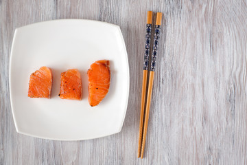 light-salted salmon on a light wooden background with Chinese chopsticks