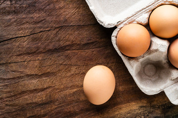 Top view of raw chicken eggs, There are arranged in a neatly organized carton box to prevent them from cracking. All placed on brown wooden table to wait for cooking.