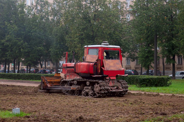 old rusty red crawler tractor leveling the ground