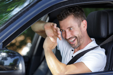 laughing man in car shading his eyes with his arm