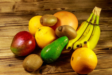 Assortment of tropical fruits on wooden table. Still life with bananas, mango, oranges, avocado, grapefruit and kiwi fruits