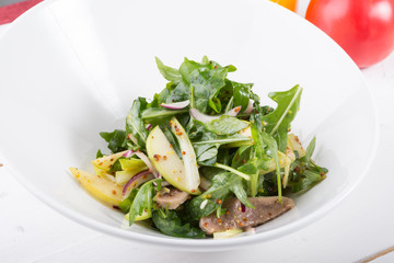 Green arugula salad with beef tongue and apple in a white bowl