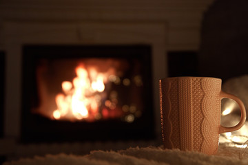 a cup of hot tea on the background of the fireplace, soft and fluffy rug, warm and cozy atmosphere