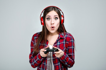 Beautiful girl with joystick and headphones on grey background