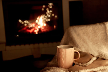 a cup of hot tea on the background of the fireplace, soft and fluffy rug, warm and cozy atmosphere