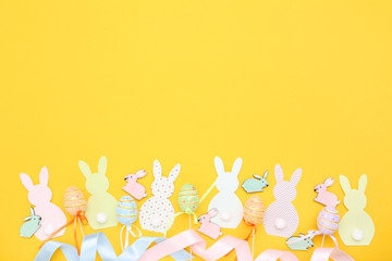 Easter rabbits and eggs on yellow background