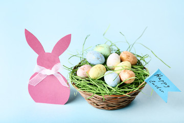 Fototapeta na wymiar Easter eggs with paper rabbit on blue background