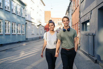 Young couple smiling while walking in the city holding hands