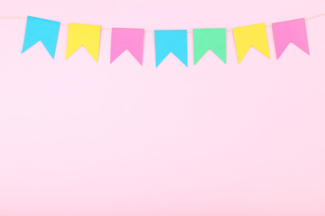 Colorful paper flags hanging on pink background