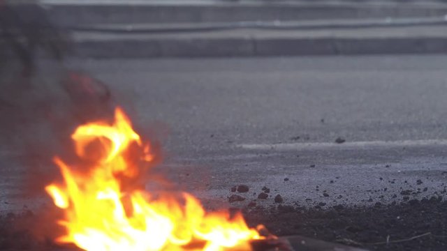 Closeup detail of flame on the street as pedestrian feet pass by