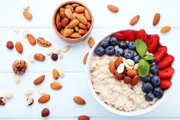 Oatmeal with berries and nuts in bowl on wooden table