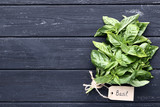 Green basil leafs with paper card on black wooden table