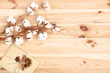 Cotton flowers with envelope, dry orange and cinnamon stick on brown wooden table