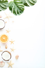 Different seashells with fruits and monstera leafs on wooden table