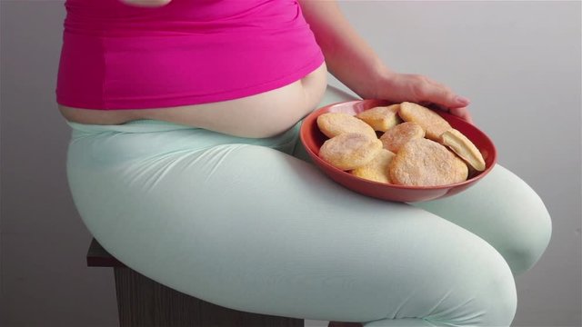 sitting hungry overweight woman eat cookies from plate close up