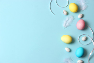  Easter composition of painted eggs and feathers on a colored background. Easter background