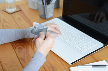 Old senior woman using laptop and holding credit card