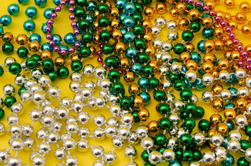 Mardi Gras beads on yellow background. Close up photo of mardi gras beads