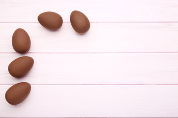 Chocolate easter eggs on pink wooden table