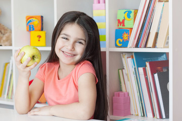 School activity, happiness and smartness.  Cute adorable child girl sitting by the table and smiling.