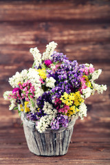 Spring flowers in basket on brown wooden table