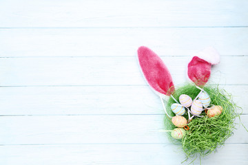 Obraz na płótnie Canvas Rabbit ears with easter eggs on wooden table