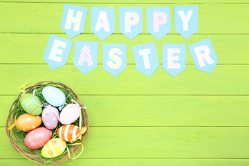 Text Happy Easter with easter eggs on green wooden table