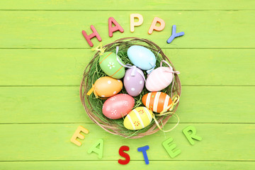 Colorful eggs with text Happy Easter on green wooden table