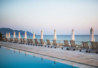 Beach chairs and umbrellas on tropical beach, summer holiday concept.